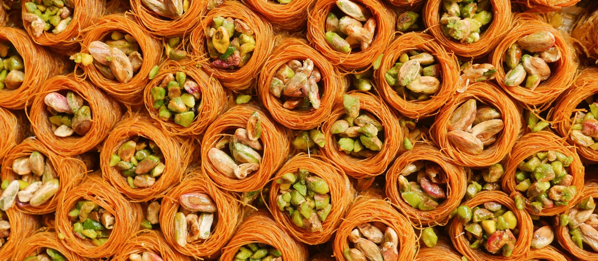 Rolled pistachio baklava packed tightly on a serving tray